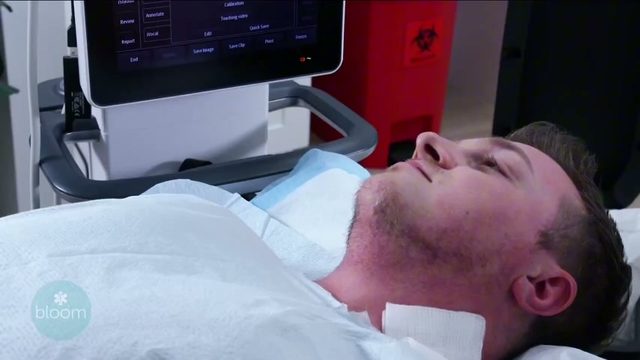A patient resting on the treatment table beside the ultrasound system